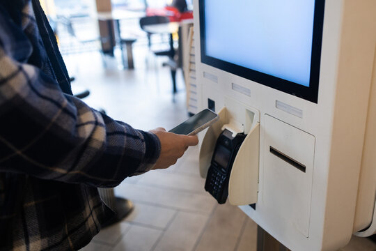 Closeup man Counter Buy electronic payment supermarket smartphone male hand with a mobile phone in pay for purchases in stores Contactless NFC Terminal Close Up card reader.