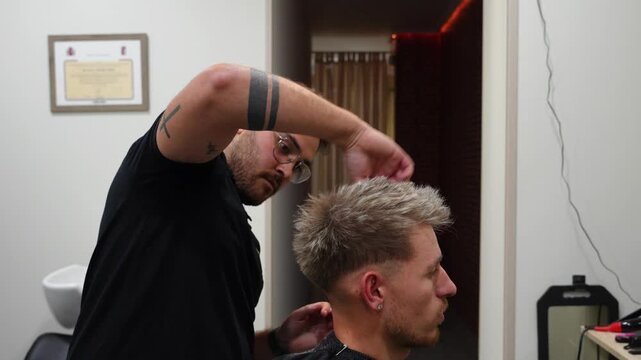 Hairdresser styles and adds finishing touches to client's hair after haircut to refine the final look