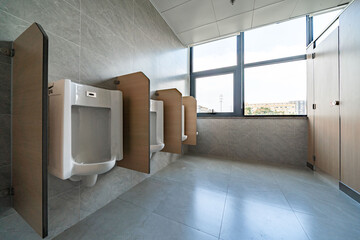 white urinal with wooden partitions, set against gray tiles in a clean men's restroom