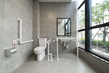 accessible bathroom with grab bars, large windows, and gray tiles