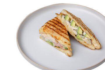 A delicious toasted sandwich, cut in half on a white plate, filled with avocado and meat