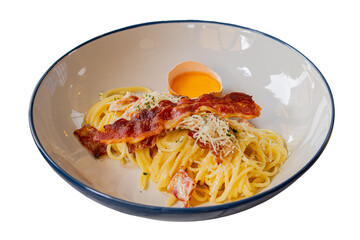 Delicious spaghetti carbonara with bacon and a cracked egg yolk, presented in a stylish bowl. The dish is visually appealing, highlighting the creamy texture and rich flavors