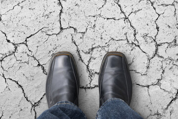 person stand on grey severely cracked floor, concept of crisis, risk, problem and unstable
