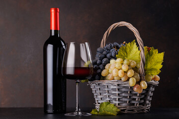 Fototapeta premium Red wine bottle with a glass and basket of fresh grapes