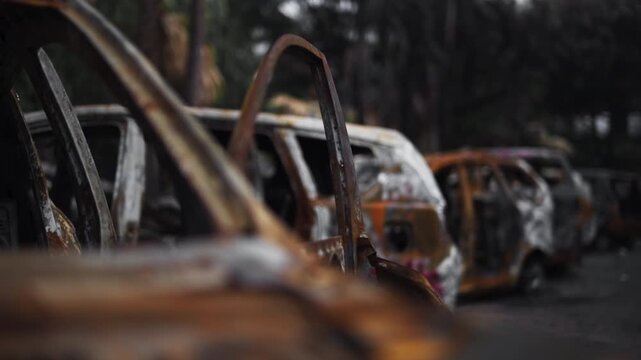 Close-up Perspective of Rusted and Burnt Car Wrecks in a Row