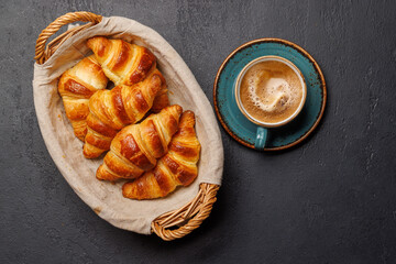 Aromatic croissants in wicker basket with cup of coffee