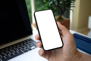 male hand holding phone with isolated screen laptop background office