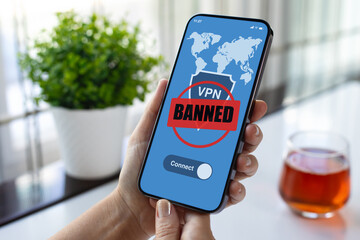 female hands holding phone with VPN banned on screen cafe