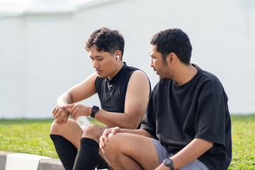 Asian Indonesian Men Resting and Drinking Water After Running