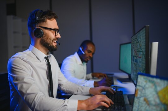 Male Data Scientist Works on Personal Computer Wearing a Headset in Big Infrastructure Control and Monitoring Room - Powered by Adobe
