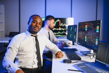 Team of traders working with forex trading charts and graphs on computer screen