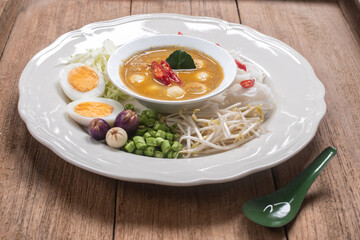 Thai rice noodles with fish ball curry sauce served with boiled eggs, bean sprouts, and fresh vegetables. Authentic Thai traditional dish known as 