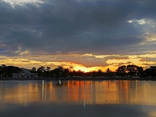 Golden Sunset over Lake: A tranquil lake mirrors a breathtaking sunset, its waters reflecting the fiery hues and silhouetted trees along the horizon, creating a scene of serenity.