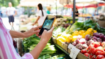 Customer scans QR code with phone for contactless payment at organic farmer’s market with glowing HUD overlay - Powered by Adobe