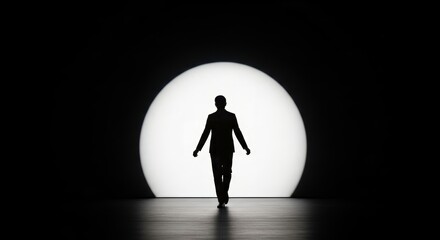 Fototapeta premium Silhouette of a confident man in a suit walking towards a large illuminated circle on stage, creating a dramatic atmosphere and highlighting the concept of performance and presence