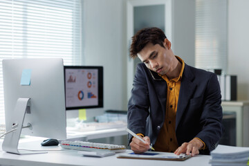 Asian businessman multitasking talking on phone writing notes