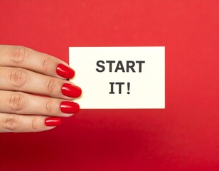 Hand holding a card that reads "START IT!" against a vibrant red backdrop