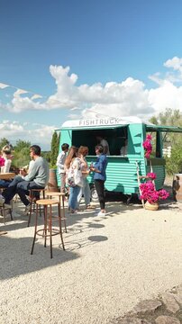 People gathering at a fish food truck during an outdoor party