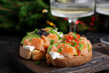 Avocado and salmon appetizer on the Christmas table. Canapes with fish and caviar.