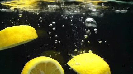 Fresh lemons falling into water creating bubbles and splash - Powered by Adobe