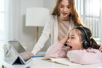 Asian bored kid daughter learning online class from home with mother.