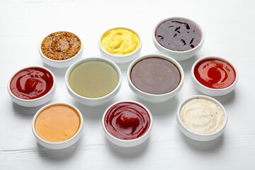 Different sauces in bowls on white wooden table