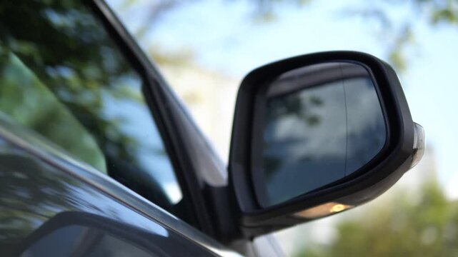 Close-up of a modern cars side mirror automatically deploying with an integrated blinking turn signal. Shot against a serene sky, this clip highlights automotive innovation, safety features, and