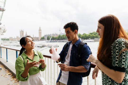 Friends enjoying cotton candy and conversation by the Thames in London