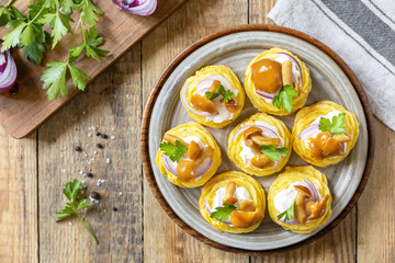 Potato tartlets filled with cottage cheese and marinated mushrooms on a rustic background. Top view.