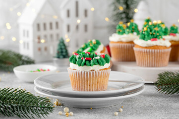 Christmas tree and wreath shaped cupcakes with candy sprinkles on top. Christmas dessert on a light concrete background.