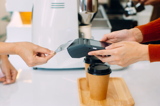 Contactless payment, Customer using credit card for making payment at cafe restaurant. Close up of woman using card for paying , shop owner receiving payment from customer in coffee shop.