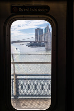 View of Manhattan skyline and Brooklyn Bridge through subway window