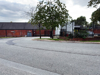 Urban street scene in Manchester UK with brick wall, trees, and metal fence
