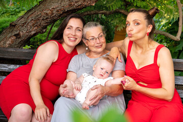 Three generations of women lovingly interacting with smiling baby girl