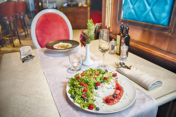 Fresh green salad with berries and cream cheese on elegant restaurant table