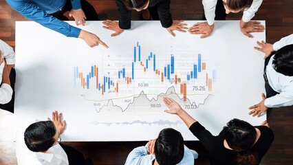 A group of business professionals gathers around a table analyzing financial charts and graphs, focusing on data for effective decision-making and strategic planning. Raster