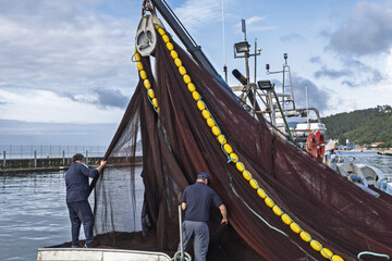 fishing boat with dark red and brown nets draped over the side in Setubal, Portugal