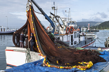 fishing boat with dark red and brown nets draped over the side in Setubal, Portugal