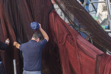 fishing boat with dark red and brown nets draped over the side in Setubal, Portugal