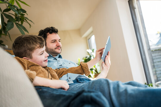 Father and son enjoying quality time together using a tablet indoors