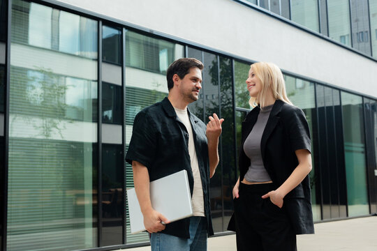 Businesswoman and software developer chatting outdoors at modern office