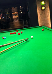Snooker balls, cue extension stick and green table in indoor  room