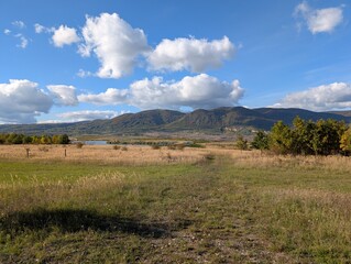 Autumn Field with a View of a Lake and Mountains