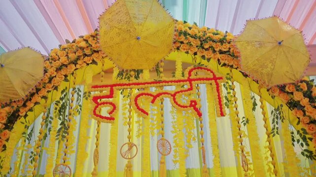 Haldi ceremony backdrop adorned with vibrant marigold flowers, floral text, and colorful Indian wedding decorations creating a festive atmosphere perfect for joyful celebrations.