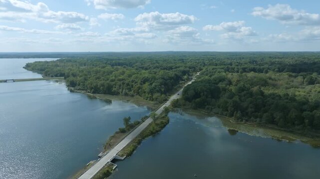 Drone push in shot flying over a lake and a road at Stony Creek Metropark in Macomb County Michigan on a beautiful fall day
