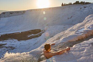 Pamukkale white mineral limestone natural pool. Man relaxing. Turkey