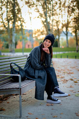 Full length of a confident middle-aged woman relaxing in a city park in an autumn day