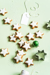 Zimtsterne Kekse mit Zuckerglasur und einem leeren Etikett auf einem hellgr&uuml;nen Hintergrund. Weihnachten, Dessert.