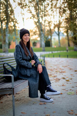 Full length of a confident middle-aged woman relaxing in a city park in an autumn day