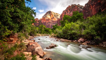 Flowing river cuts through a lush valley, framed by tall, rugged red rock mountains under a bright, cloudy sky